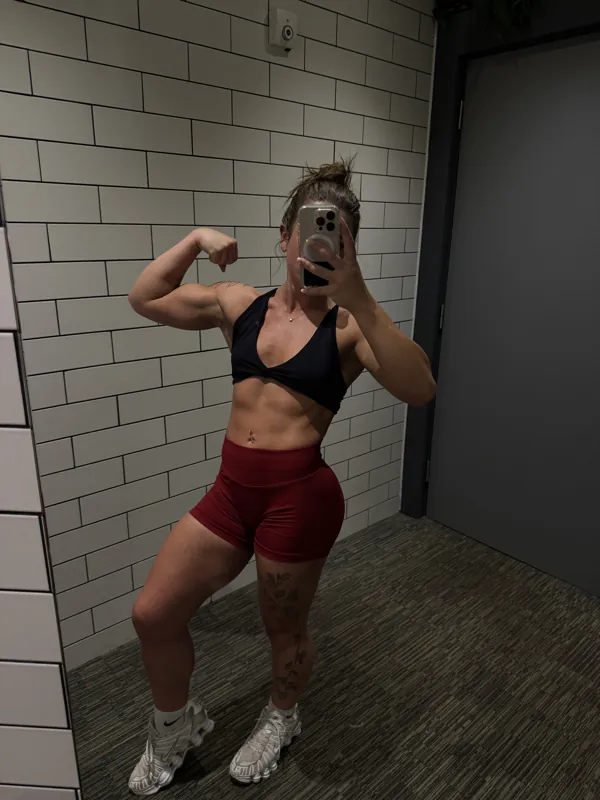 thickmouse9 flexing at the gym in a black sports bra and red shorts